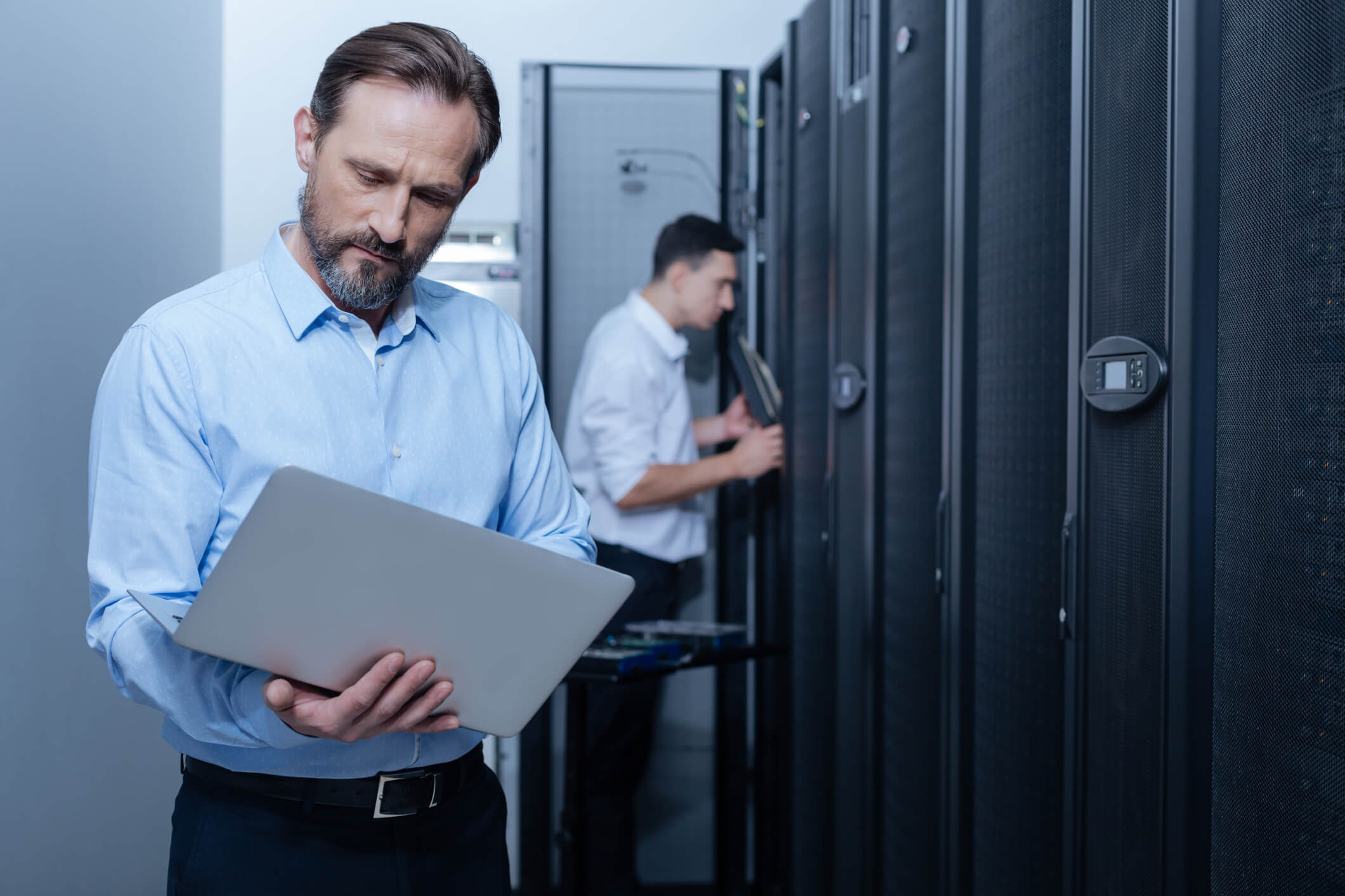 IT employee working on a laptop in a server room