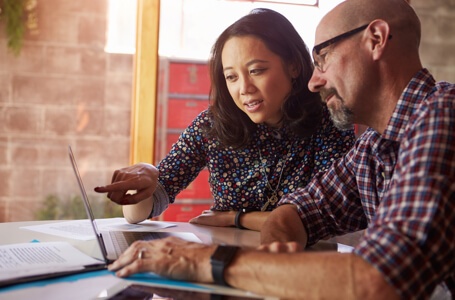 Two person discussing tech in front of laptop